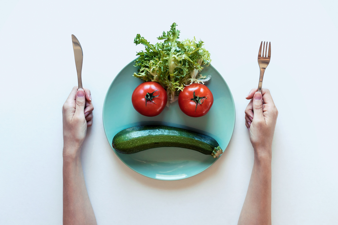 Sad face of vegetables in plate. The concept of dietary restrictions, healthy lifestyle, diet, weight loss, anti-obesity, healthy diet.